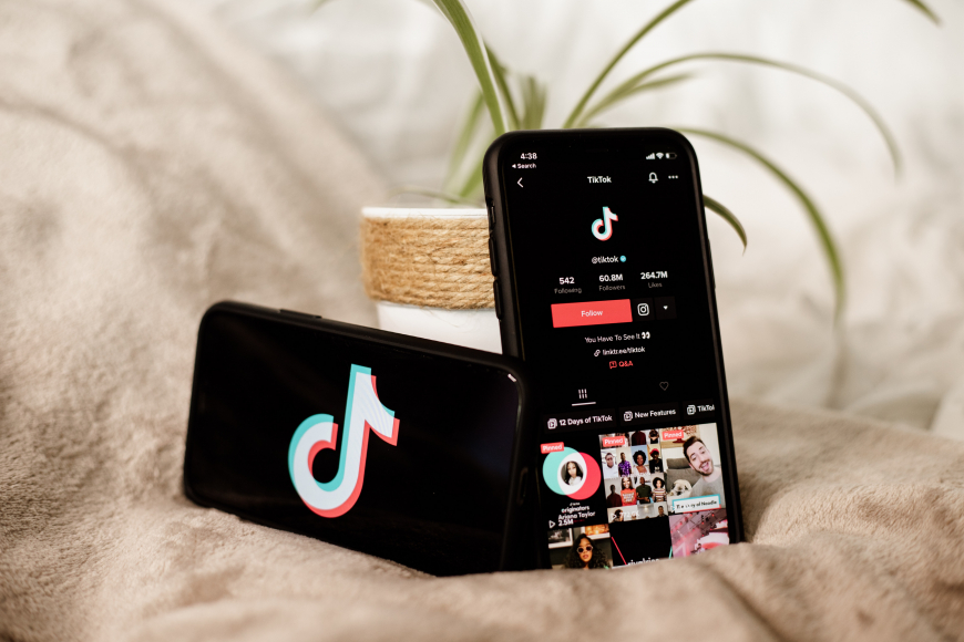 Two phones side by side, the left displaying the TikTok logo, the right one displaying TikTok's profile page
