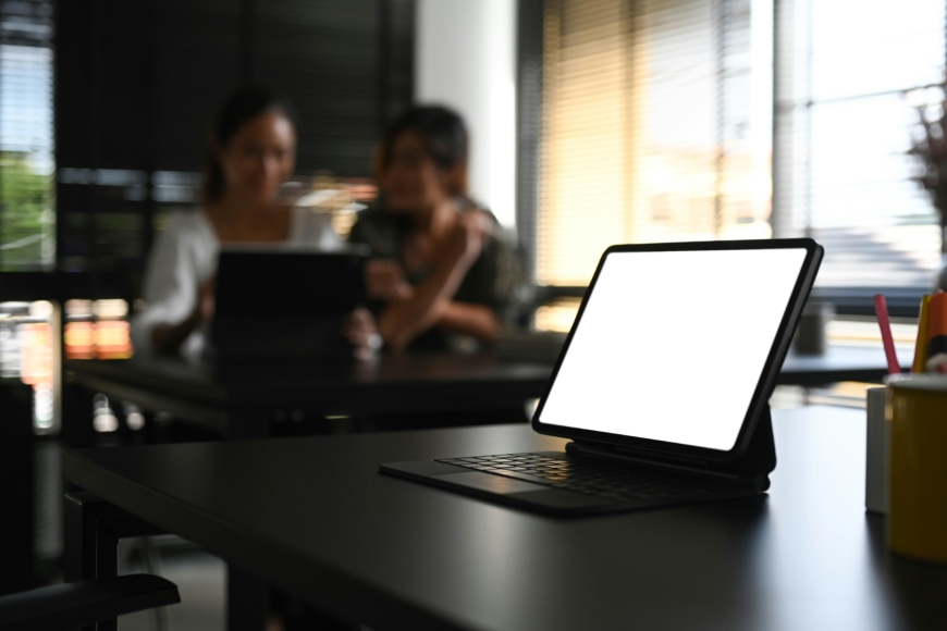 Computer screen on a desk with people in the background